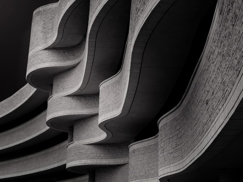 A low angle greyscale of a building with modern brutalist architecture under the sunlight